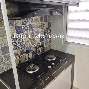 a kitchen with a black counter top with tiles on the wall at D' Palm Garden Homestay Lahad Datu. in Lahad Datu