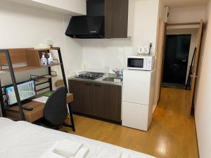 eine kleine Küche mit einem weißen Kühlschrank und einer Mikrowelle in der Unterkunft ホワイトテラス桜新町 in Tokio