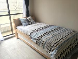 ein Bett in einem Schlafzimmer neben einem Fenster in der Unterkunft ホワイトテラス桜新町 in Tokio