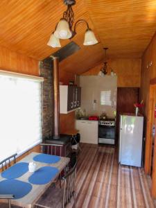 a kitchen with a table and a refrigerator at CABAÑAS LOS CASTAÑOS in Los Ángeles