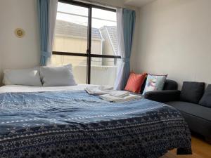 ein Schlafzimmer mit einem Bett, einem Sofa und einem Fenster in der Unterkunft ホワイトテラス桜新町 in Tokio