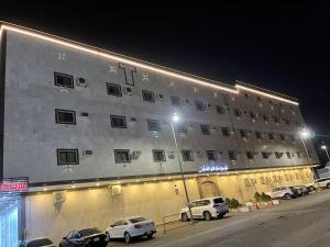ein großes Gebäude mit davor geparkt in der Unterkunft شقق سويت ستار الفندقية in Tabuk
