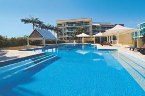 a large blue swimming pool with a hotel in the background at The Entrance Waterfront Apartment 621 in The Entrance