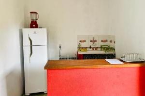 cocina con nevera blanca y encimera roja en Pousada Aquarela, en Caraíva