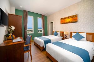 a hotel room with two beds and a desk at Shara Hotel Da Nang in Da Nang
