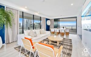 sala de estar con sofá blanco, sillas y mesa en The Wave - QStay en Gold Coast