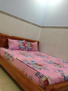 ein Bett mit einer rosa Bettdecke und Kissen in der Unterkunft Nhà nghỉ Ngọc Duy Bến Tre in Ben Tre