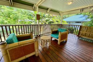 a porch with two chairs and a table on a deck at Fare Manamana iti - The Magic Mountain's bungalow - 2 bdr - 4 pers - wifi in Papetoai