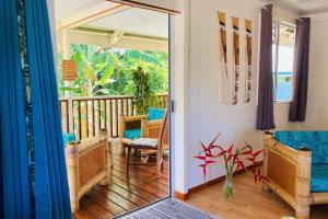 an open door to a balcony with chairs and surfboards at Fare Manamana iti - The Magic Mountain's bungalow - 2 bdr - 4 pers - wifi in Papetoai