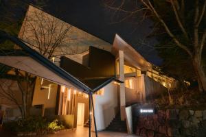 a house with a staircase in front of it at night at Fourtreat Kusatsu in Kusatsu