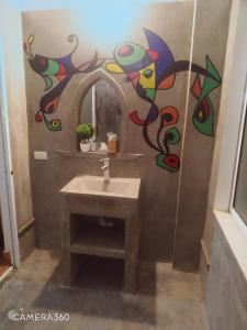 La salle de bains est pourvue d'un lavabo et d'une peinture murale. dans l'établissement Phong Nha Midtown hotel, à Phong Nha