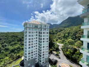 a tall white building with mountains in the background at Santubong Suites A Just Like Home Damai in Kuching