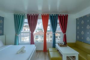 - une chambre avec des rideaux rouges et bleus, un lit et une table dans l'établissement Ken's Backpackers Hotel, à Đà Lạt