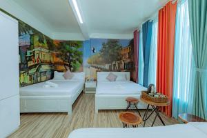 Cette chambre comprend deux lits et un tableau mural. dans l'établissement Ken's Backpackers Hotel, à Đà Lạt