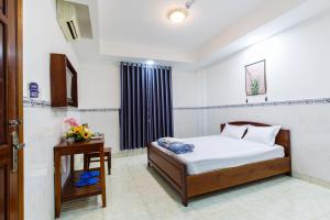 a bedroom with a bed and a table and a window at Hoa Cúc Phương Hotel Dĩ An - Bình Dương in Dĩ An