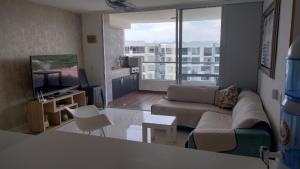 sala de estar con sofá y TV en Acogedor Apartamento en Ricaurte con BBQ, en Girardot