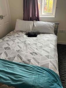 a bed with a black and white comforter and a window at Centralized Complete 3 BR Flat at Newcastle-Under-Lyme with a View-Free Parking in Newcastle under Lyme