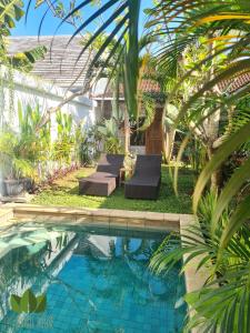 a swimming pool with chaise lounges next to a house at The Jungle House in Canggu