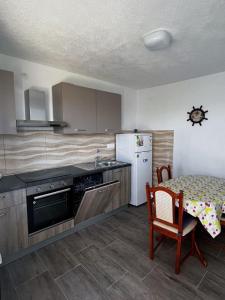 a kitchen with a table and a white refrigerator at Apartments Dalibor - 5m from the sea with parking in Lukovo Šugarje