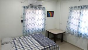 1 dormitorio con cama, mesa y cortinas en Neighbour's Nest, en Sāngli