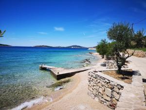 einen Strand mit einer Steinmauer und dem Meer in der Unterkunft Apartments Delfin - sea view in Prvić Šepurine