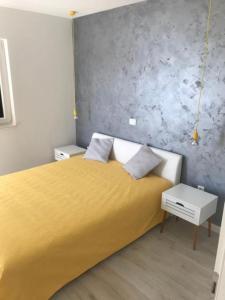 a bedroom with a yellow bed and a gray wall at Apartments Delfin - sea view in Prvić Šepurine