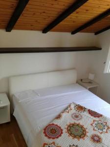 ein Schlafzimmer mit einem weißen Bett mit einer Decke darauf in der Unterkunft Apartments Njoko - sea view in Prvić Šepurine
