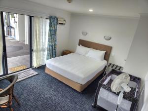 a bedroom with a large bed and a balcony at Botany Palms Motel in Auckland