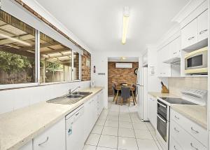 a kitchen with white cabinets and a table in it at Floreat in Sawtell