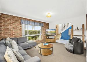 una sala de estar con un sofá y una mesa en Floreat, en Sawtell