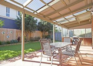 a patio with a table and chairs under a pergola at Floreat in Sawtell