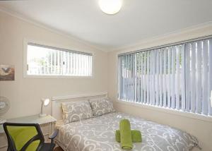 Un dormitorio con una cama y un escritorio y una ventana. en Floreat, en Sawtell