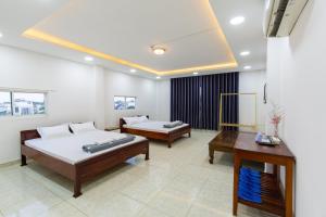 a bedroom with two beds and a table in it at Hoa Cúc Phương Hotel Dĩ An - Bình Dương in Dĩ An