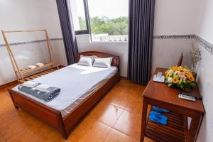 um quarto com uma cama e uma mesa com flores em Hoa Cúc Phương Hotel Dĩ An - Bình Dương em Dĩ An