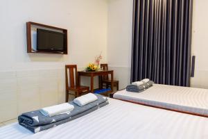 a hotel room with two beds and a tv at Hoa Cúc Phương Hotel Dĩ An - Bình Dương in Dĩ An