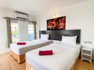 The Palace Aonang Resort في شاطيء آونانغ: غرفة نوم بها ثلاثة أسرة مع ملاءات بيضاء ووسائد حمراء