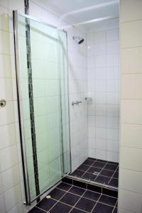 a bathroom with a glass shower with black tiles at Coconut Grove Holiday Apartments in Darwin