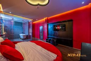 Dormitorio rojo con cama y TV en Midas Hotel en Ho Chi Minh