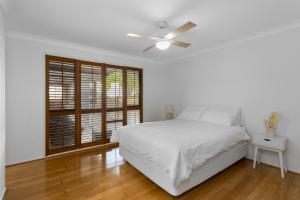 ein weißes Schlafzimmer mit einem Bett und einem Deckenventilator in der Unterkunft Spacious 4 Bedroom Entire Home with Pool - Robina, Gold Coast in Gold Coast + 11 Fotos