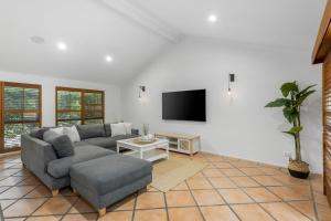 ein Wohnzimmer mit Sofa und Fernseher in der Unterkunft Spacious 4 Bedroom Entire Home with Pool - Robina, Gold Coast in Gold Coast