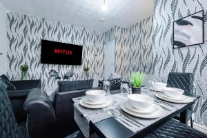 una sala da pranzo con tavolo e divano di 65 Inch TV & Luxurious 2 Bedroom Suite for Your Ultimate Getaway a Bradford