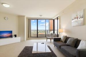 a living room with a couch and a tv at Large elevated apartment St Leonards in Sydney