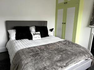 a bed with black and white blankets and pillows at Warm and cosy city centre home near train station in Chichester