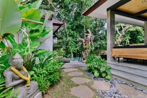 ウブドにあるVilla Gaya Ubudのベンチ横の像のある庭園