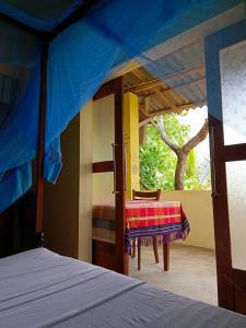 1 dormitorio con cama, mesa y ventana en Three Little Birds, en Tangalle