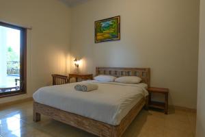 a bedroom with a large bed with white sheets and a window at The Uma Canggu in Canggu