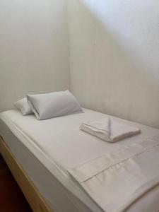 Una cama con sábanas blancas y almohadas. en Puente Real Hostel, en Liberia