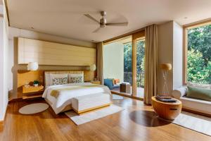 デヘラードゥーンにあるSix Senses Vana - A Wellness Retreatの大きなベッドと大きな窓のある寝室