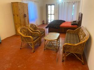 Habitación con sillas de mimbre, mesa y cama en Brook Cottage, en Champawat