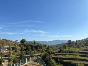 a view of a valley with a fence and mountains at Brook Cottage in Champawat